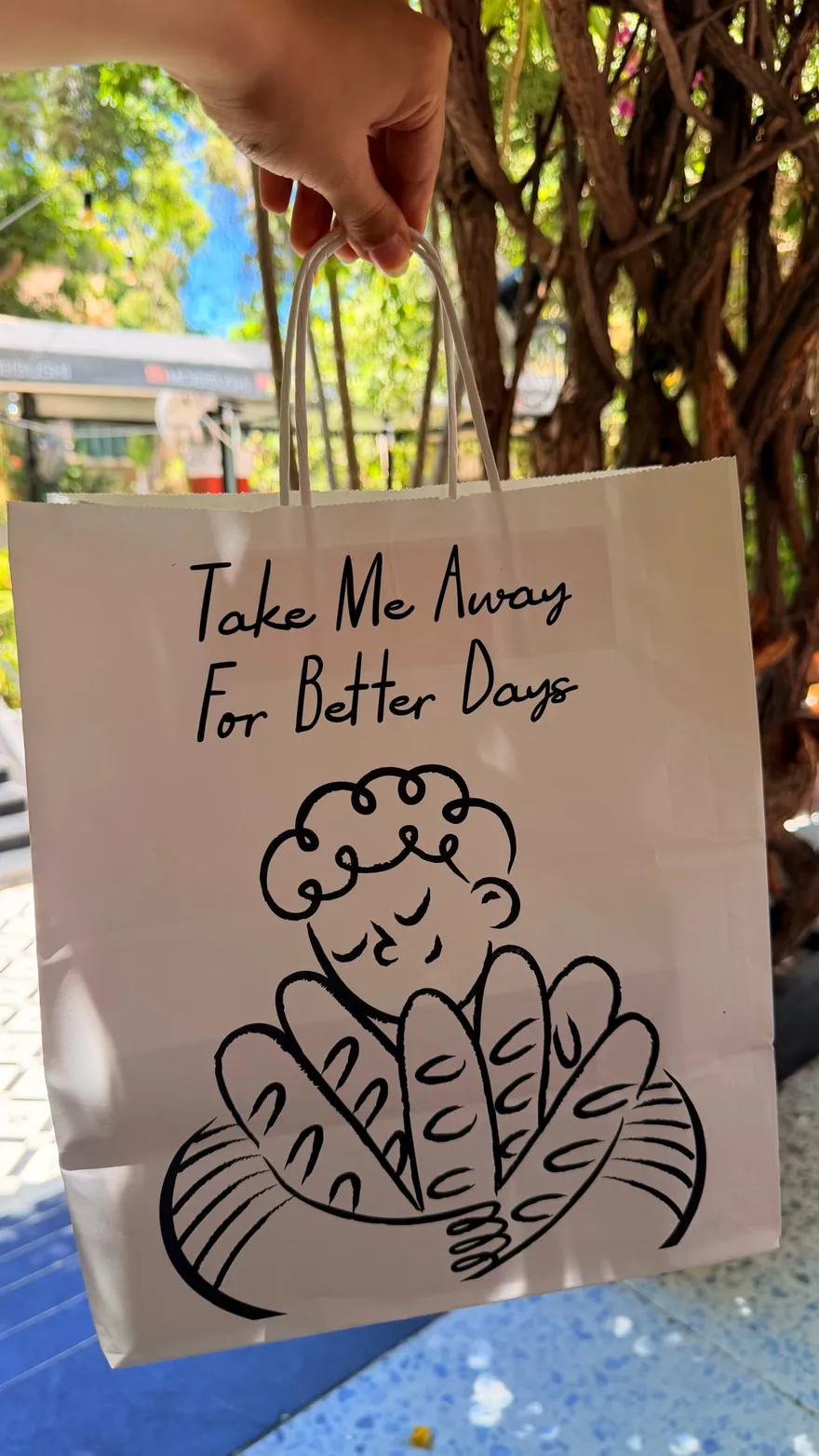 A kraft Villa 9 takeaway bag printed with the words Take Me Away For Better Days.