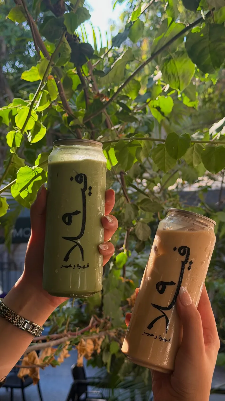 Two iced coffees held up against the plants outside Villa 9.